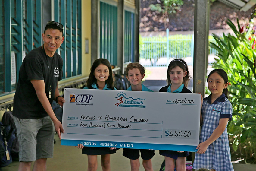 photo of Som receiving donation from Year 3s at St Andrew's Catholic College 